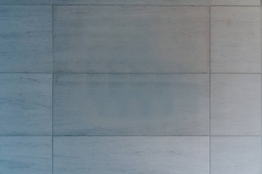 Gri beton panellerden yapılmış, pürüzsüz yüzeyi olan ve birbirine kolayca uyan bina duvarının minimalist arka planına yakın plan.