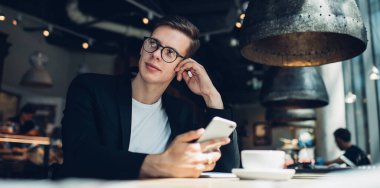 Resmi kıyafetli, gözlüklü, elinde cep telefonu ve sıcak içecekle oturan rüya gibi restoran yöneticisinin elinden.