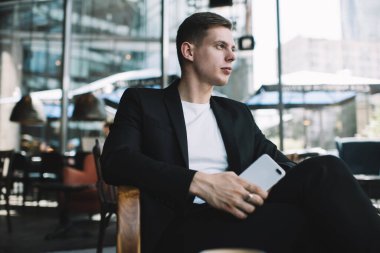 Resmi ceketli ve rahat koltukta oturan ve uzaktan çalışma sırasında mola veren kendine güvenen erkek girişimcilerden.