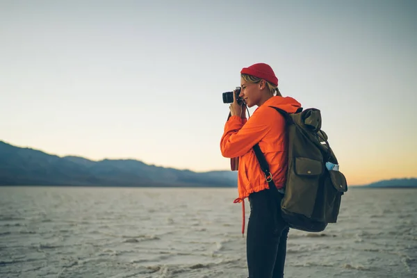 Turuncu Ceketli Genç Bayan Fotoğrafçının Dağ Sırasının Yakınındaki Tuz Arazisinde — Stok fotoğraf