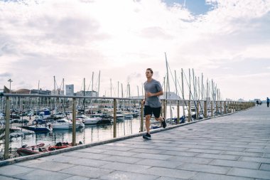 Eşofmanlı güçlü erkek koşucu vücudunu formda tutmak için aktif ve sağlıklı yaşam tarzını sürdürüyor. Sabahları sokakta beyaz sporcu eğitimi alıyor.