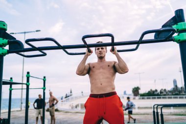 Kaslı erkek sporcu antrenman için boş vaktini harcıyor ve güçlü vücudunu barfiks çekmeye zorluyor. Kafkas sporcusu seksi gövde egzersizi yapıyor. Amaçlarına ulaşmak için antrenman yapıyor.
