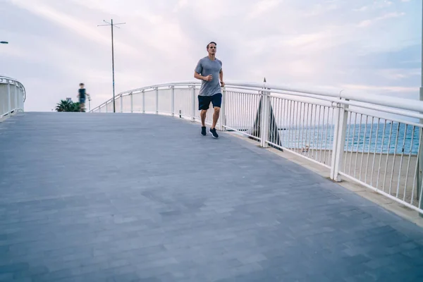 朝の痩身エネルギーを取得し 積極的なトレーニング心臓の屋外で深刻な強い男性ランナー ハンサムな白人スポーツマンは 痩身のための健康的なライフスタイルを維持するために橋の上にジョギング — ストック写真