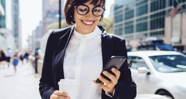 Tarlada stil sahibi, şık takım elbiseli, gözlüklü, akıllı telefon kullanan ve New York 'un caddesinde kahve içen bir kadın.