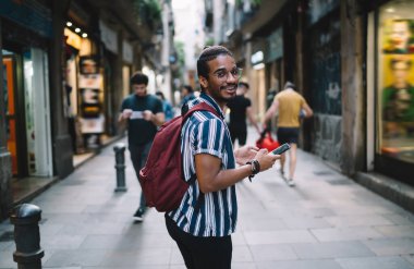 Sokakta yürürken ve omzunun üzerinden bakarken gözlüklü ve gözlüklü bir adamın cep telefonuyla mesajlaşması