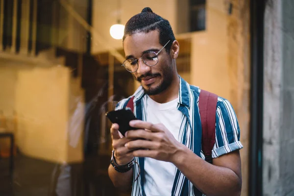 積極的な暗い肌の暗い肌のヒップスター男は 路上での接続に満足ブログでコンテンツを共有 笑顔アフリカ系アメリカ人男性インフルエンサースマートフォンでコンテンツをダウンロード屋外 — ストック写真