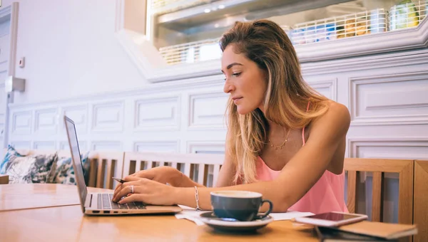 Skoncentrowana Chuda Kobieta Różowym Top Wpisując Netbooku Patrząc Ekran Podczas — Zdjęcie stockowe