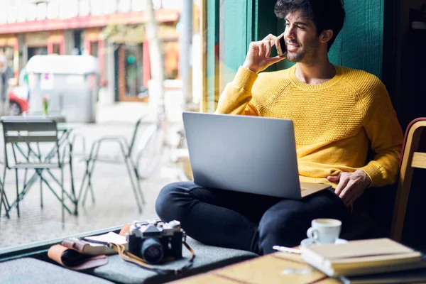 Zufriedene Freiberufler Lässiger Kleidung Sitzen Mit Laptop Holztisch Und Telefonieren — Stockfoto