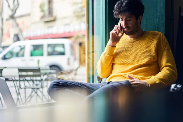 Thoughtful Ethnic Male Casual Outfit Sitting Cozy Cafe Speaking Mobile — Stock Photo, Image