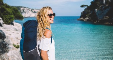 Kaygısız Kafkas kadın sırt çantalı gezgin, Balear adalarının kıyılarındaki nefes kesen Menorca 'da İspanyol doğasını keşfetmek için seyahat macerasının tadını çıkarıyor.