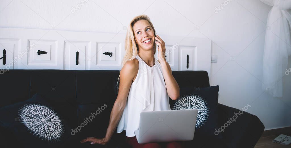 Successful Caucasian influence blogger calling to friend for discussing social publication made on website via modern netbook technology, cheerful freelancer enjoying smartphone communication indoors