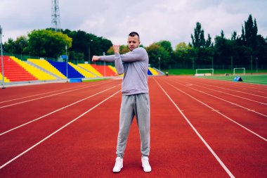 Aktif giyimli güçlü beyaz erkek vücudunun üst kısımları için ısınma egzersizleri yapıyor. Egzersiz için hazırlanıyor. Yakışıklı hippi sağlıklı yaşam tarzını koruyor.