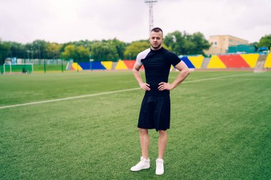 Formda kalmak için aktif eğitimden sonra stadyumda poz veren yakışıklı erkek sporcunun yarım boy portresi. Genç ve güçlü bir adam kameraya bakıyor. Aktif sağlıklı yaşam tarzını sürdürüyor.