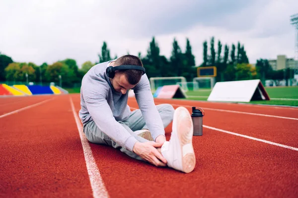 Νεαρός Καυκάσιος Αθλητής Ακουστικά Που Τεντώνουν Σώμα Για Τρέξιμο Χρήση — Φωτογραφία Αρχείου