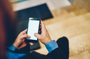Online rezervasyon ve bankacılık için internet reklamları için fotokopi alanı olan cep telefonu cihazını kullanan erkek işadamının kesilmiş görüntüsü, boş ekranlı akıllı telefon aygıtı üzerine seçici odaklanma