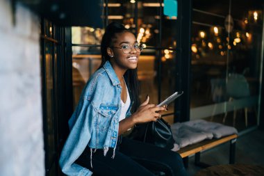 Gözlüklü, at kuyruklu ve kameraya gülümseyen neşeli Afro-Amerikan kadın manzarası.