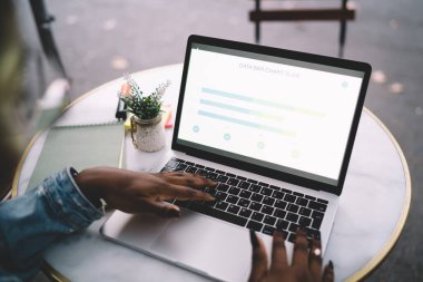 Gündüz vakti elinde defter ve kalemle masada otururken netbook kullanan anonim Afrikalı Amerikalı kadın serbest yazar.