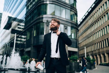 Stresli sakallı, resmi takım elbiseli, dar kravatlı ve sıcak kahve içerken yüzünü çeviren iş adamının alçak açısı.