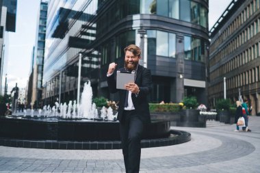 İş anlaşmasının sonuçlarından gerçekten memnun olan resmi takım elbiseli heyecanlı adam ofis binasının yanındaki modern parkta mola verdi.