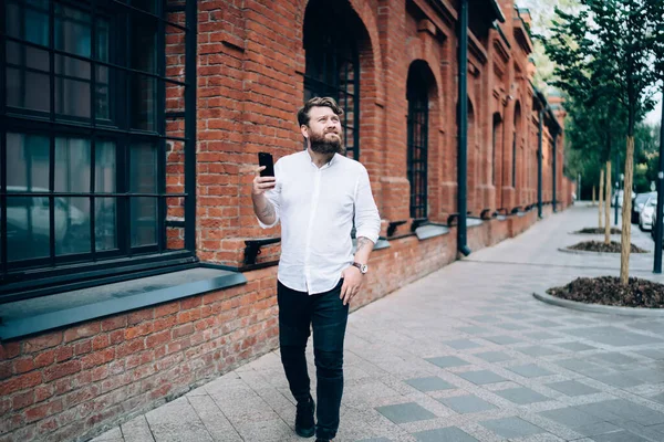 Positive Adult Man Beard Casual Clothes Using Smartphone Looking Away — Stock Photo, Image