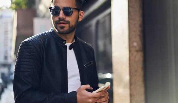 Crop Serious Bearded Male Trendy Leather Jacket Sunglasses Using Mobile — Stock Photo, Image