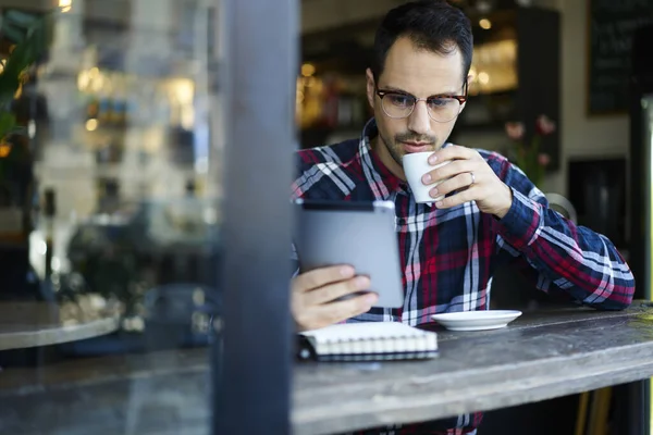 Pensiv Mannlig Fjernarbeider Hverdagsklær Briller Som Drikker Varm Kaffe Surfer – stockfoto