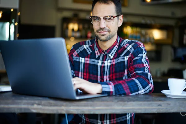 Content Bearded Male Casual Outfit Glasses Sitting Wooden Table Laptop — Stock Photo, Image