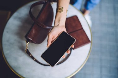 Günümüz dijital tabletini elinde tutan kadının üst görünümü tarama ve iletişim için 4G internete bağlıdır, yukarıdaki resimde ise çantalı ve defterli kadın eli ve akıllı telefon görüntüsü vardır.