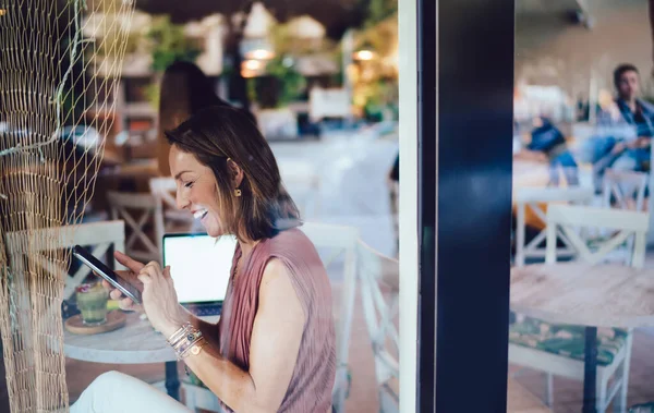 Gjennom Glasssidevisning Positiv Kvinnelig Surfe Mobiltelefon Mens Hun Sitter Med – stockfoto