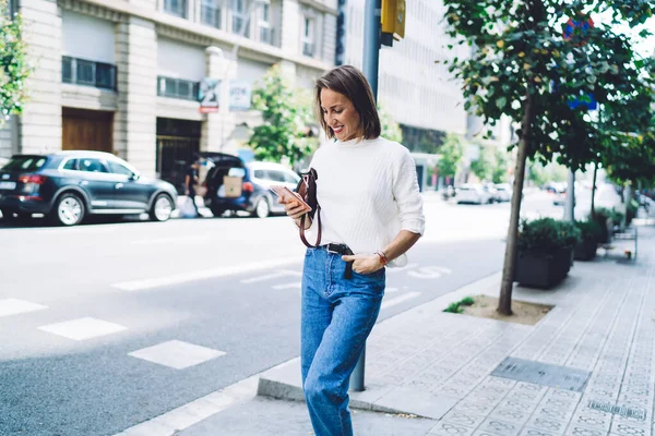 Senhora Feliz Roupa Casual Usando Celular Rua Enquanto Caminhava Mão — Fotografia de Stock