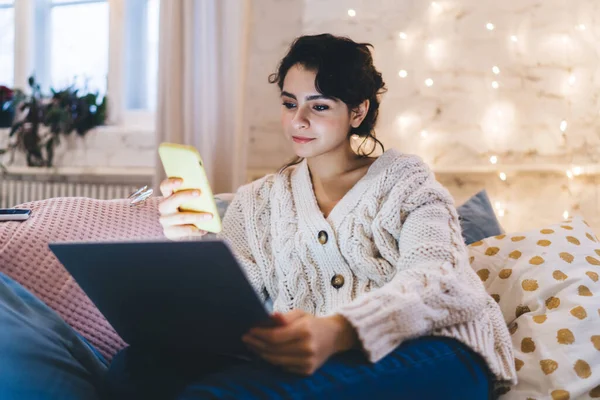 Cheerful Young Woman Knitted Warm Sweater Sitting Pillows Laptop Messaging — Stock Photo, Image