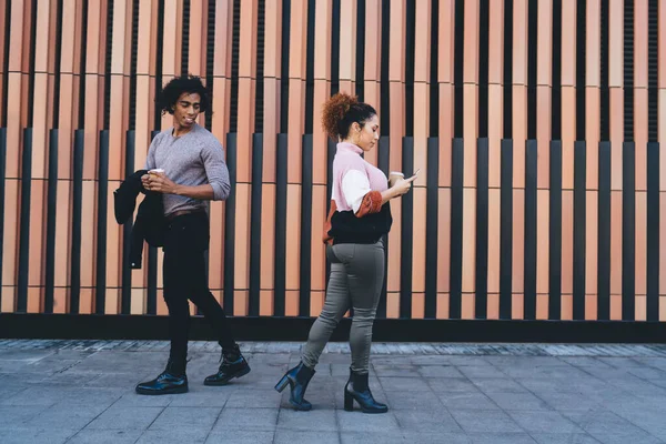 身穿休闲装 站在现代建筑附近边走边喝咖啡的积极的非洲裔美国夫妇的侧影 — 图库照片