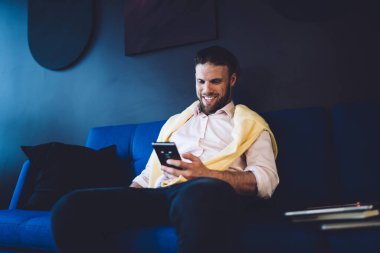 Başarılı bir adam cep telefonu aygıtı ile çevrimiçi mesajlaşma sırasında gülümseyen akıllı günlük kıyafet içinde, neşeli erkek çalışan web iletişimi ve bankacılık için 4G kablosuz bağlantı ile akıllı telefon kullanıyor