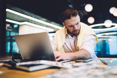 Kafkasyalı adam zamanı kontrol ediyor ve dizüstü bilgisayarda iş yaparken modern cep telefonu cihazında tebligat aldı. Yetenekli iş adamı senkronize cihazlarda 4G kablosuz bağlantı kullanıyor.