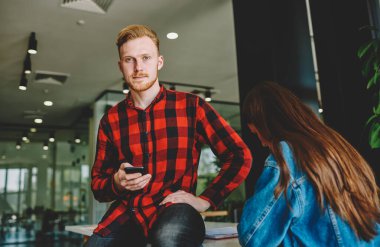 Elinde cep telefonu olan beyaz saçlı beyaz bir adamın yarım boy portresi masa başında oturan yakışıklı bir erkek blogcu elinde modern akıllı telefon ile internete bağlanıyor.