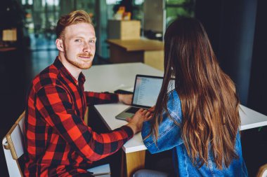Moda gömlekli yetenekli beyaz programcının portresi. Özel ders sırasında kadın kullanıcı ile birlikte yazılım geliştirme için kameraya bakıyor. Mesafeli iş yapmak için işbirliği yapıyor.