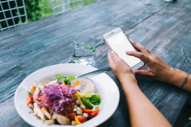 Kafe 'de nefis salatayla ahşap masada otururken boş ekranlı akıllı telefonlu isimsiz bir bayanın göz gezdirmesinden.