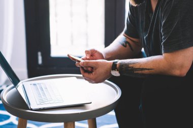 Günümüz rahat çalışma sahasında bilgisayar üzerinde çalışırken, cep telefonuyla internette sörf yapan, günlük kıyafetlerle tanınmayan erkek serbest yazar.