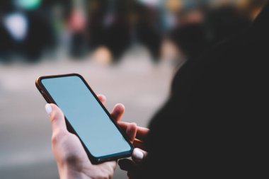 Gündüz vakti sokaklarda dolaşırken, elinde cep telefonu olan ve mesajları kontrol eden kimliği belirsiz bir kadın.