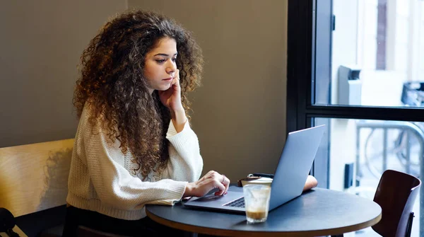 身着休闲装 聚精会神地坐在木制桌旁 在笔记本电脑上为远程项目工作的女性自由职业者的侧视图 — 图库照片