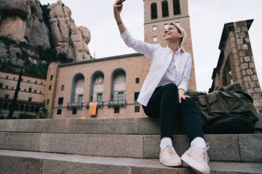 Sırt çantasıyla merdivenlerde dinlenirken, sırt çantasıyla selfie çeken ve İspanya 'yı gezen tüm vücudun altından.