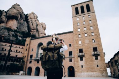 İspanya 'da yaz tatili boyunca gezerken yaşlı anıtın fotoğrafını çeken kimliği belirsiz kadın sırt çantasından arka plan görüntüsü