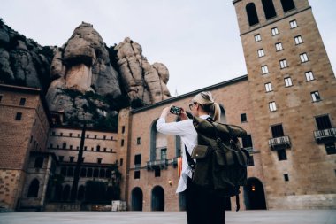 İspanya 'da zaman geçirirken tarihi binanın ve şehir merkezinde dinlenme yerinin fotoğrafını çeken tanınmamış bir kadın yolcunun arka plan görüntüsü.