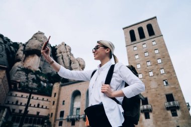 Kollarını kaldırıp Katalonya 'da İspanyol turizminin yakınında selfie çeken, günlük kıyafetlerle gezen pozitif kadın turistlerin düşük açısı.