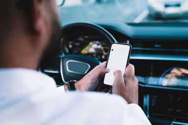 Otomobilde oturan ve akıllı telefondan iş projesiyle ilgili mesaj atan ve trafikte dikilen ekin erkek girişimcilerin arka planı