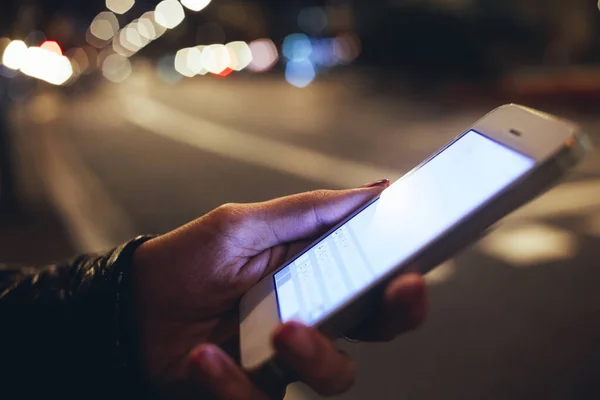作物匿名の女性で携帯電話上でマニキュアメッセージを持ちながら 夜の時間に明るい照明街の通りで時間を過ごす — ストック写真