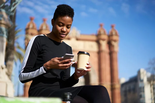 バルセロナの公園で晴れた日にリラックスしながら移動する携帯電話やコーヒーを飲みながら 少数民族の女性の下から — ストック写真