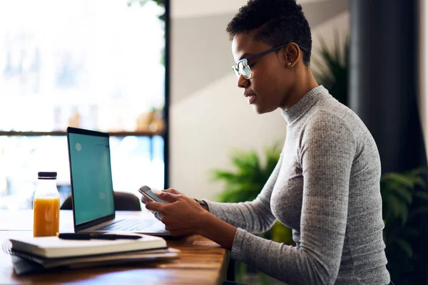 Widok Boku Skoncentrowany Afroamerykanka Freelancer Wiadomości Smartfonie Siedząc Przy Biurku — Zdjęcie stockowe