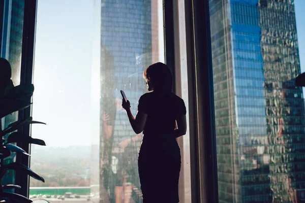 Bakåt Bild Affärskvinna Står Nära Panoramafönster Kontorsinteriör Och Chatta Mobiltelefon — Stockfoto