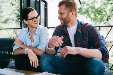 Düşük açılı, neşeli, yetişkin bir adam neşeli bir kadına komik bir hikaye anlatıyor. Güneşli bir günde, balkondaki kanepede, bulanık yeşil ağaçlara karşı otururken.